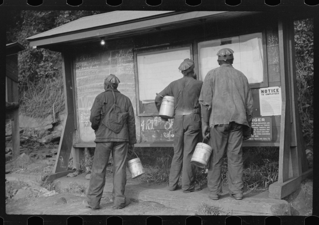 Miners looking at daily reports, checking the number of tons of slate and coal they loaded during their shift. Also to find out whether or not they work the next day. Caples, West 