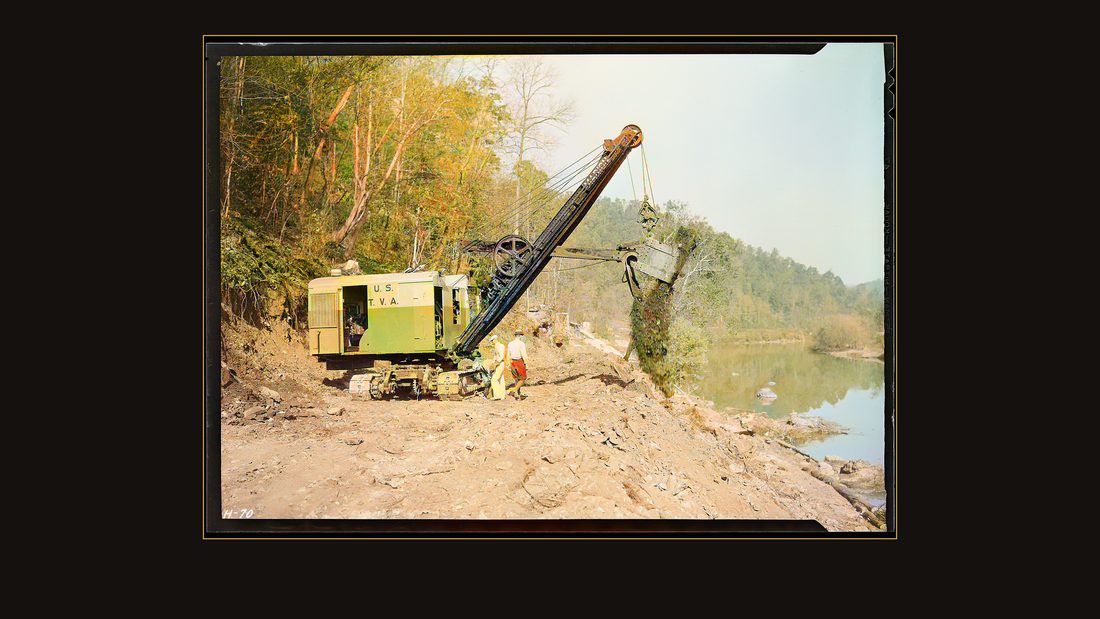 "Making the dirt fly at Norris Dam site. A power shovel working on the roadway at the Dam."