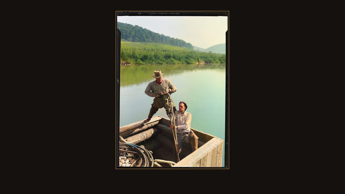 "Rock-driller and helper drilling in rock under water at Norris Dam site."