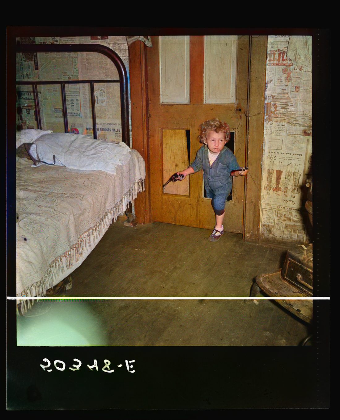 Why open the door, coal miner's child uses the "cat hole." Bertha Hill, West Virginia (Note pipe in one hand, gun in other)