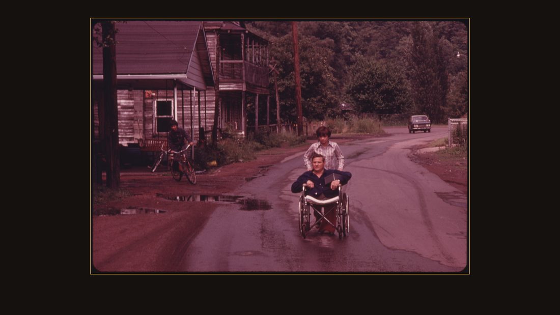 JACK SMITH, 42, A DISABLED MINER IN RHODELL, WEST VIRGINIA, IS WHEELED DOWN THE STREET BY HIS DAUGHTER, DONNA, 16, TO THE BEER JOINT HE OPERATES. HE HAD WORKED IN THE MINES FOR ONE