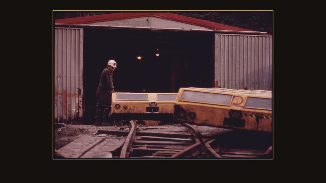 THE GENERAL MINE FOREMAN AT ONE OF THE TENNESSEE CONSOLIDATED COAL COMPANY MINES NEAR JASPER AND CHATTANOOGA STANDS BESIDE THE SHUTTLE CARS USED TO TRANSPORT THE MINERS TO WORK. TH