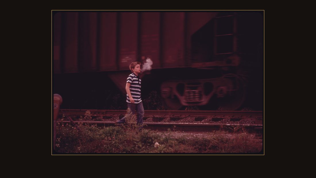 THE COOL MORNING AIR CONDENSES A BOY'S BREATH AS HE WALKS ALONG A COAL CAR ON HIS WAY TO SCHOOL IN CUMBERLAND, KENTUCKY, IN HARLAN COUNTY. COAL MINING REMAINS THE LARGEST SING